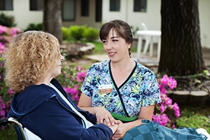 A nurse with a patient in a courtyard at Whitney Oaks